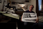 Danziger in his studio with a US flag cartoon